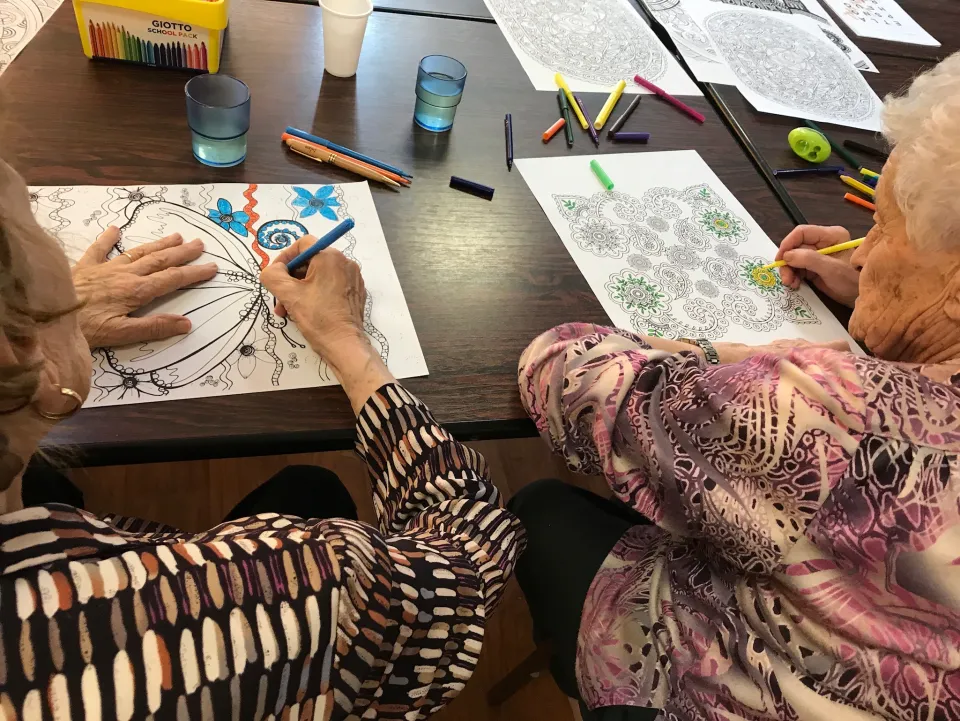 Deux participantes colorient des motifs floraux et un mandala autour d’une table.